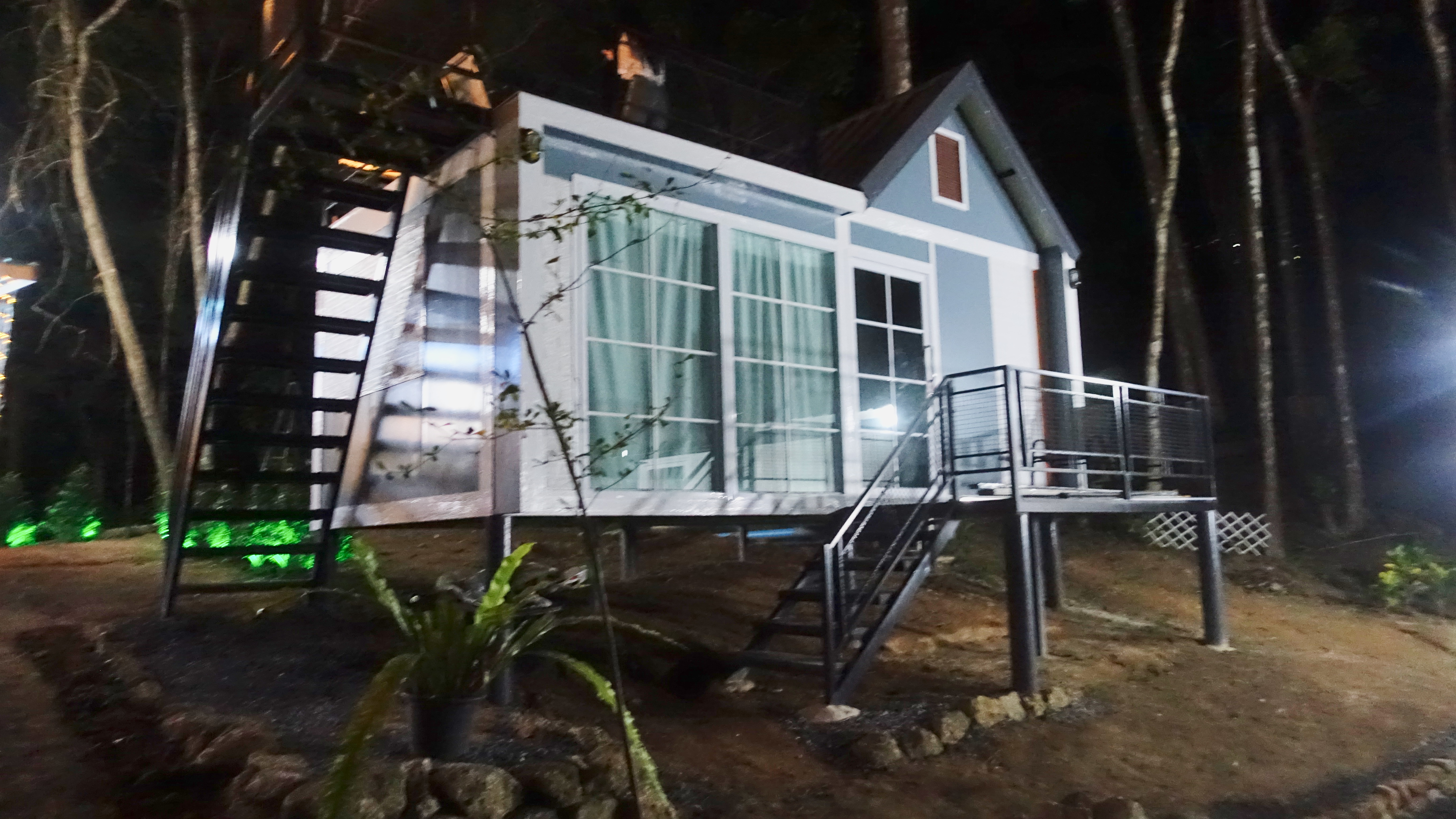 Night exterior view of illuminated deluxe bungalow with green accent lighting