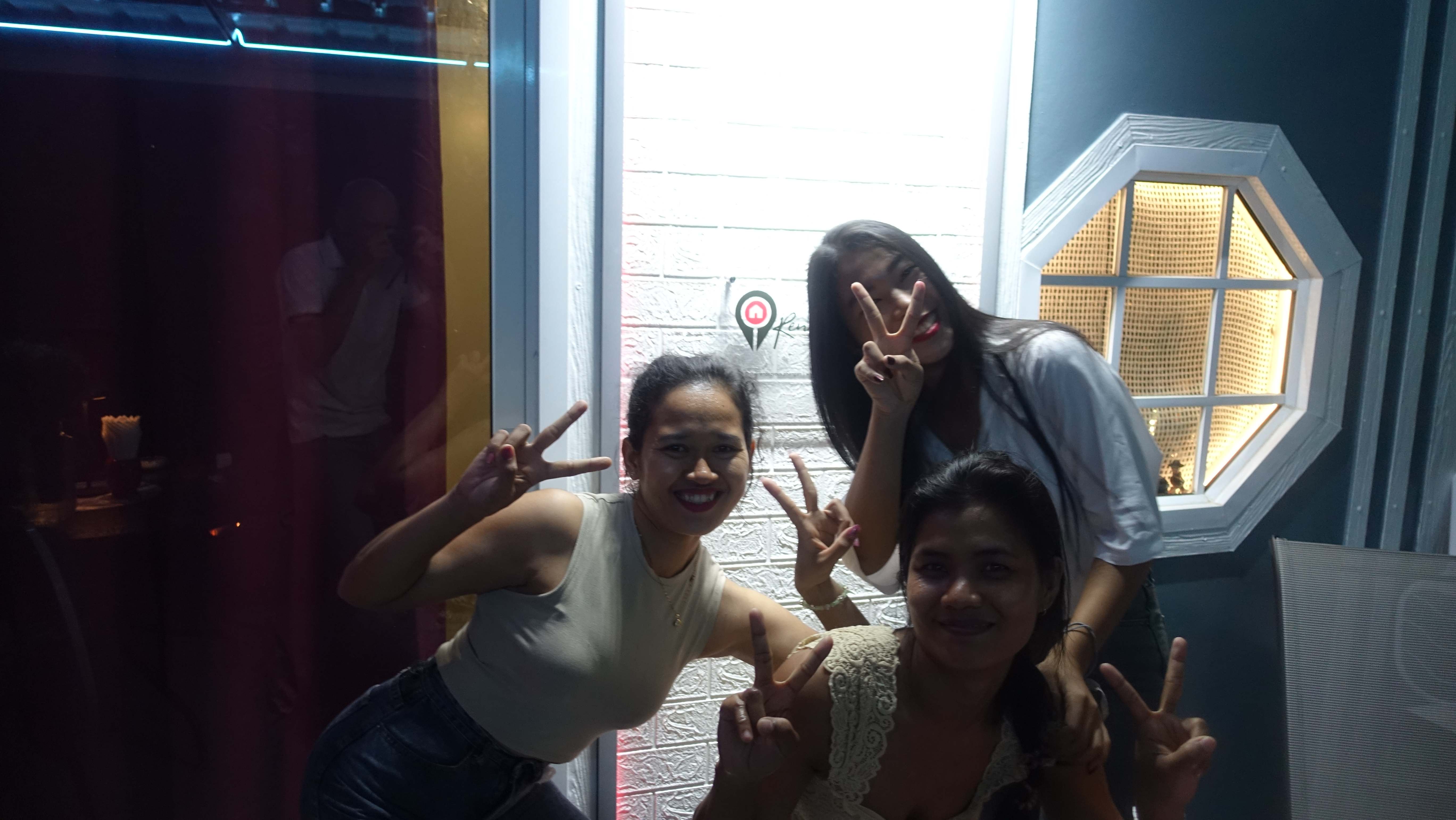 Three female guests making peace signs and having fun indoors