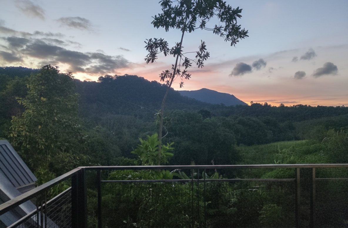 Sunset view from deluxe bungalow balcony overlooking jungle mountains